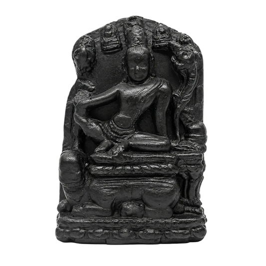 A small black stone or resin statue of a seated Buddha figure with ornate halo-like details behind it, photographed against a plain white background.